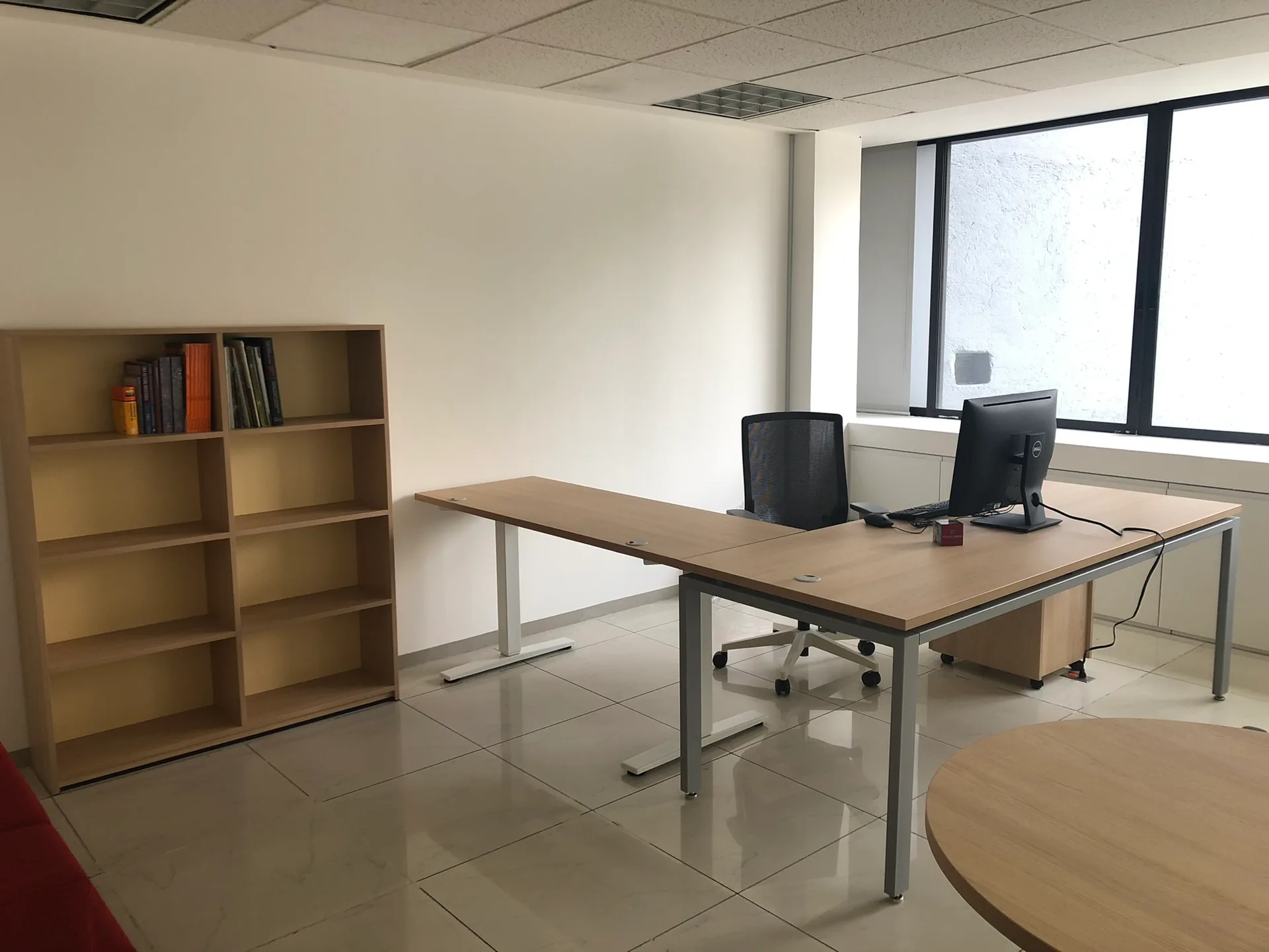 Privado de Harvard con escritorio en L de madera, librero abierto y mesa redonda, por Poliarte
