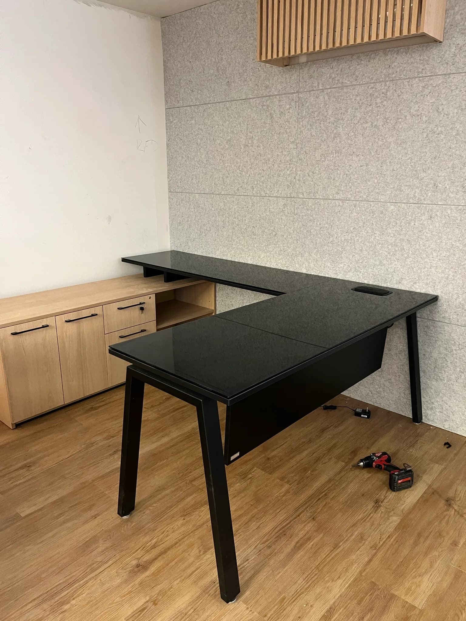 Escritorio en L de Capdeville con cubierta negra, patas negras y credenza de madera, por Poliarte