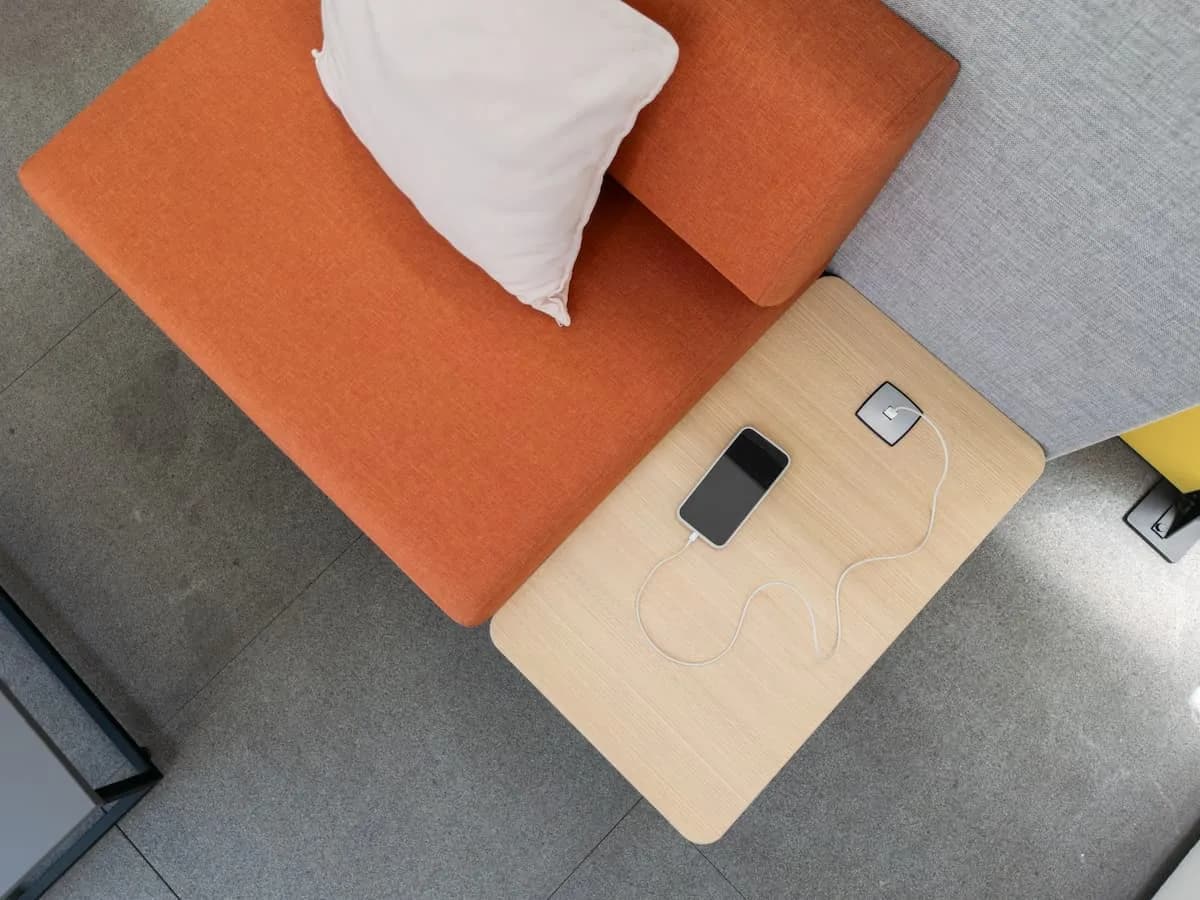 Sofá modular naranja con mesa auxiliar de madera y cargador integrado, visto desde arriba