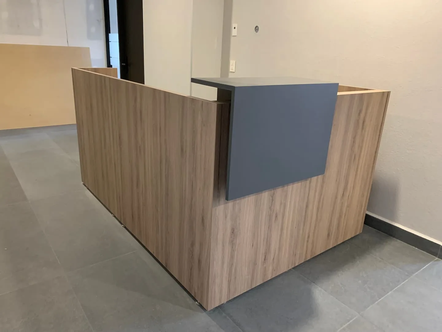 Recepción de DIMSA en madera clara con mostrador gris oxford, mobiliario de Poliarte