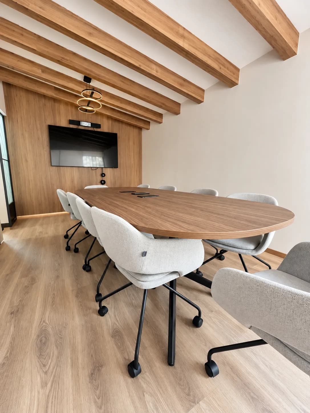 Errece Studios: sala de juntas con mesa ovalada de madera, sillas tapizadas y muro de madera