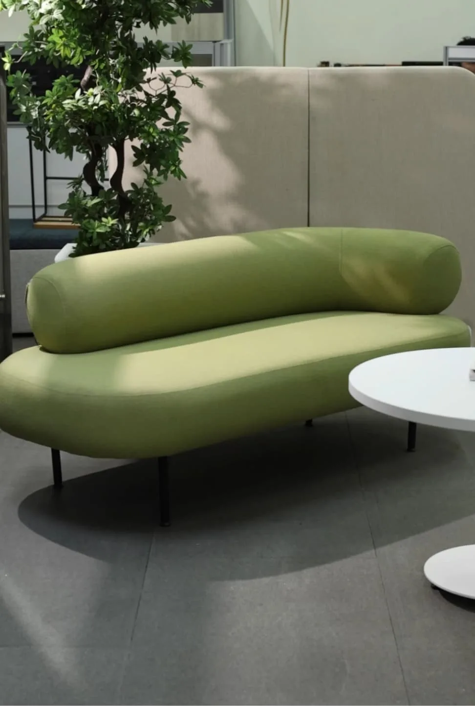 Sofá lounge verde con mesa auxiliar en el showroom de Poliarte