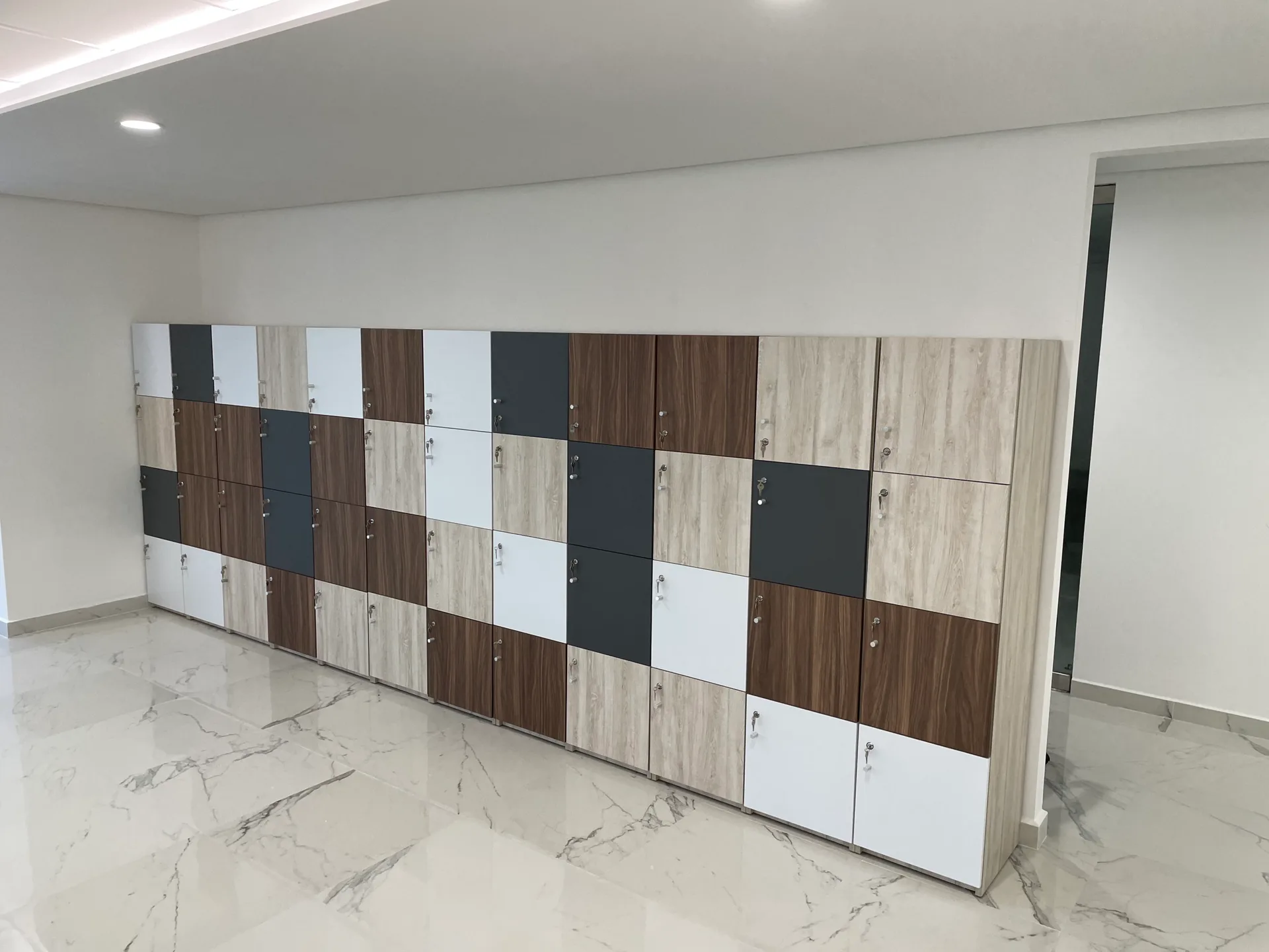 Lockers de Cayeno en tablero de madera, blanco y gris oxford a lo largo del muro, por Poliarte