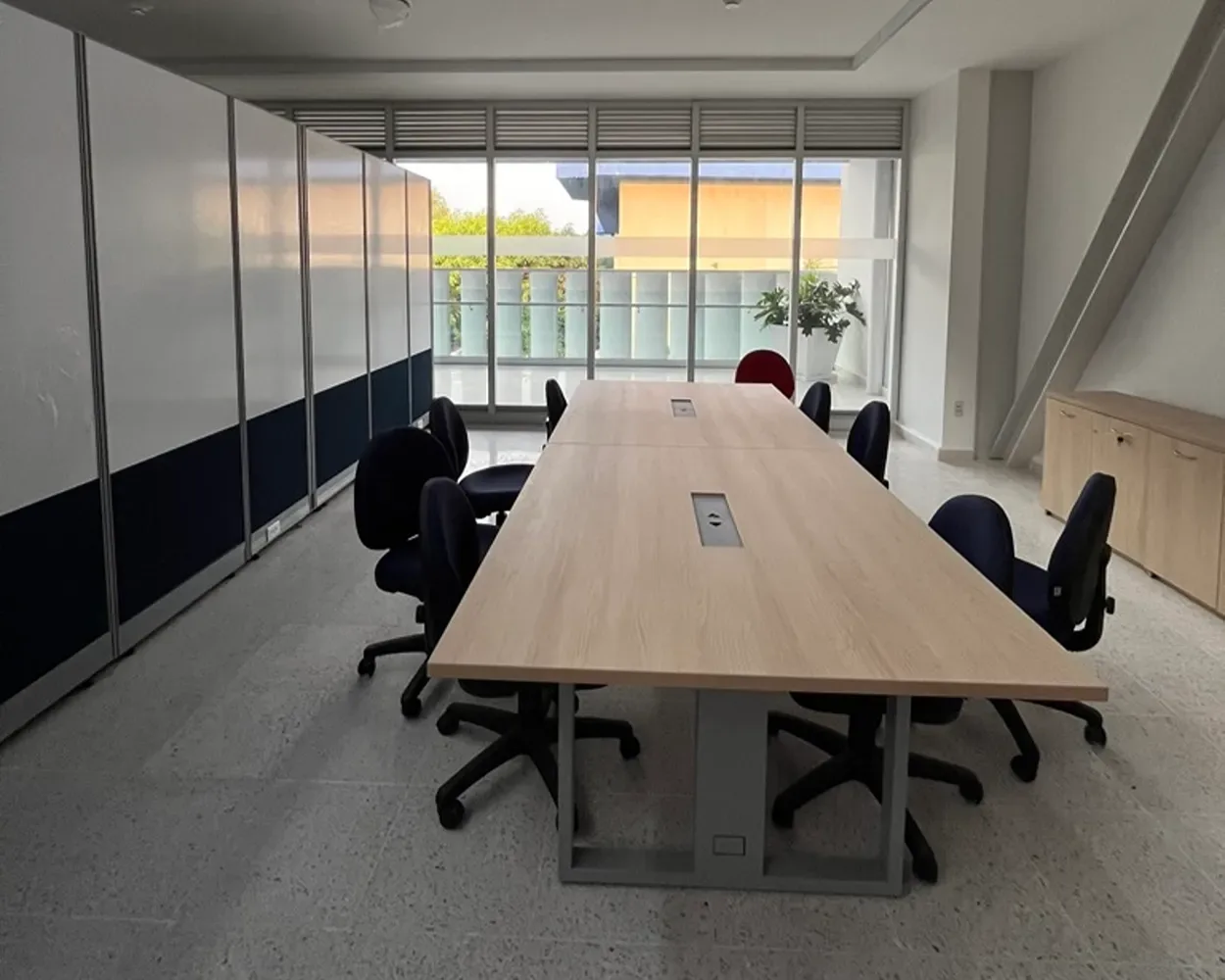 Sala de juntas de La Salle con mesa larga de madera clara y sillas negras, por Poliarte