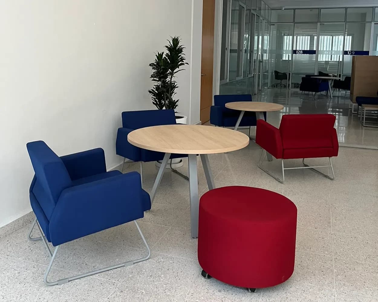 Área de descanso de La Salle con sillones azules y rojos, puff y mesa redonda, por Poliarte
