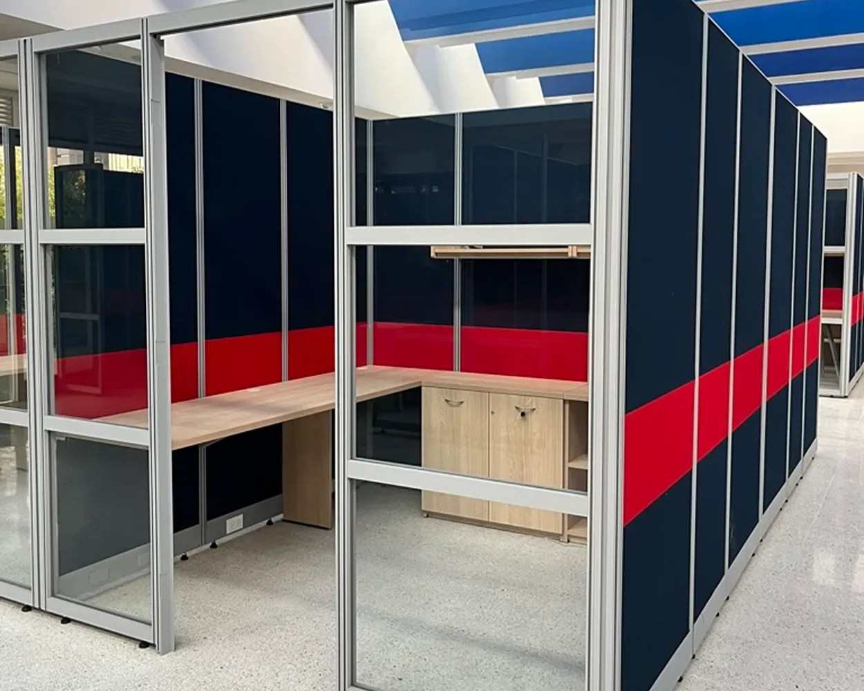 Cubículos de La Salle con muros divisorios azul marino y rojo, cubiertas de madera y gabinetes, por Poliarte