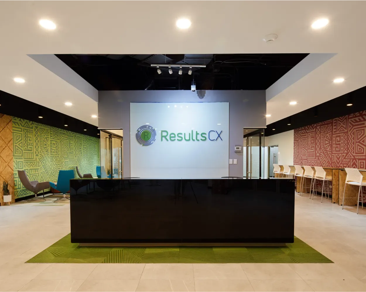 Recepción negra de Newcore Industries frente al logo de ResultsCX, con lounge a los lados, por Poliarte