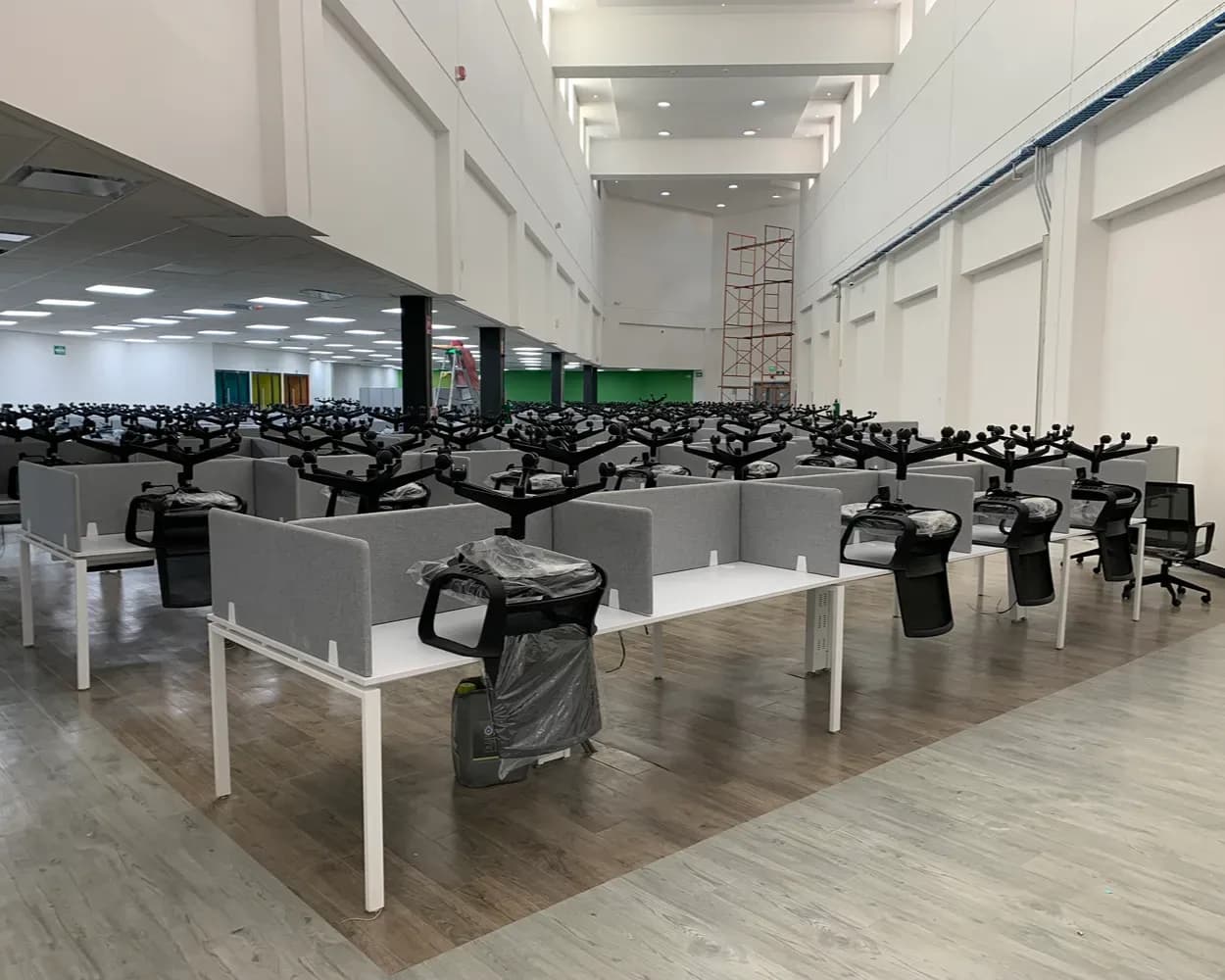 Piso de Newcore Industries en instalación con estaciones blancas y mamparas grises en hileras, por Poliarte