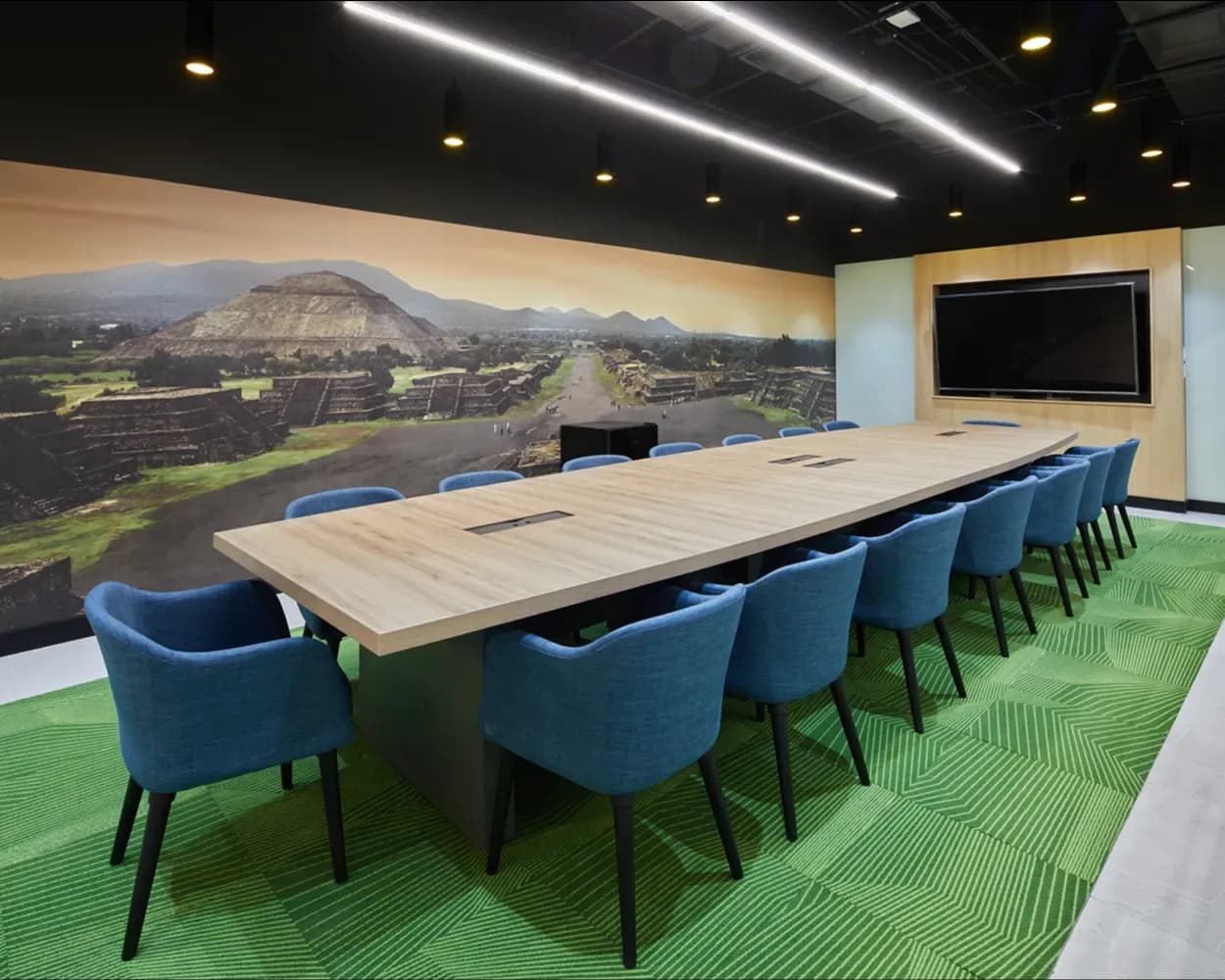 Sala de juntas de Newcore Industries con mesa larga de madera y sillas azules tapizadas, por Poliarte