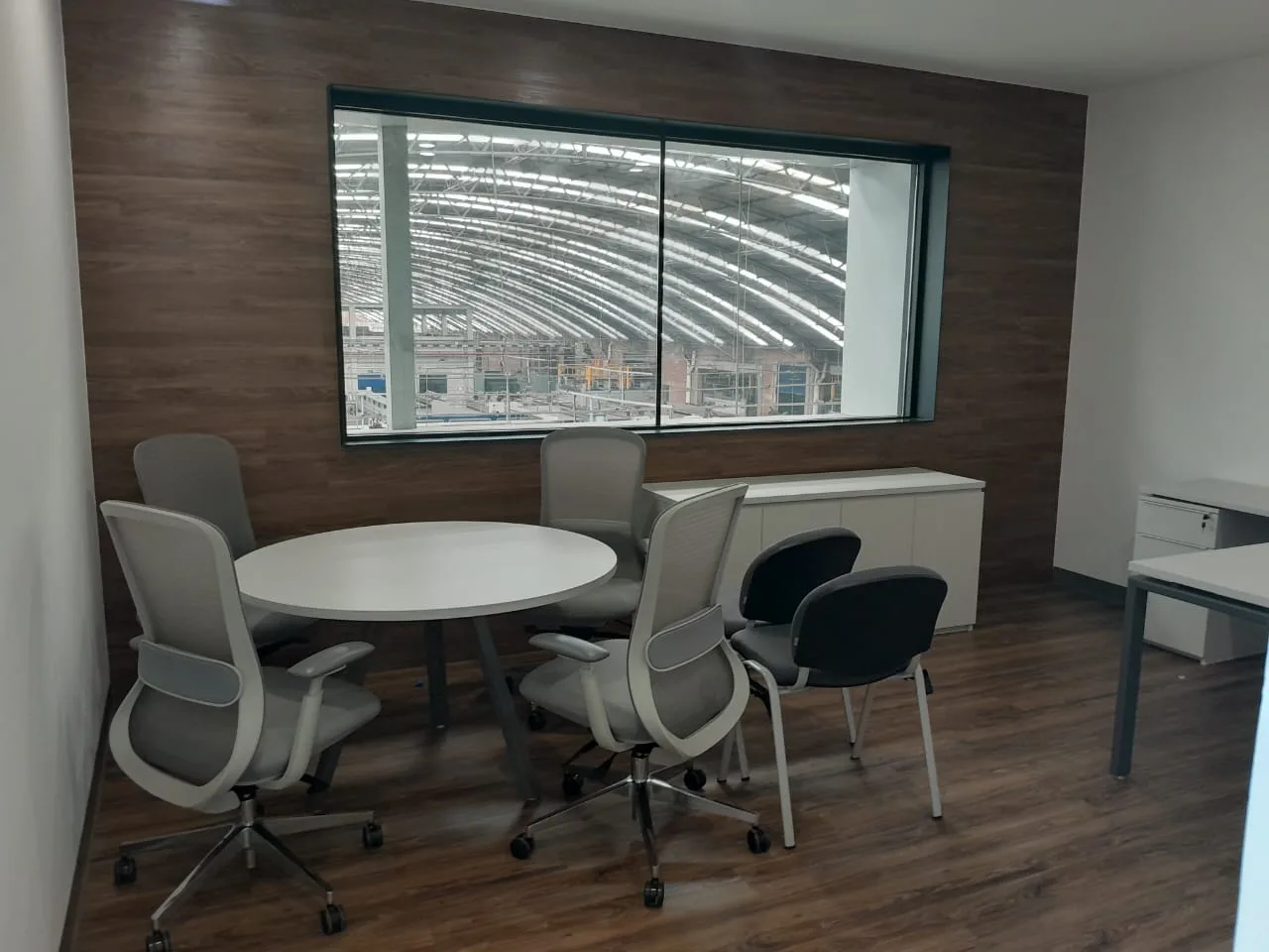 Sala de juntas pequeña de BA Glass con mesa redonda blanca y sillas grises, por Poliarte