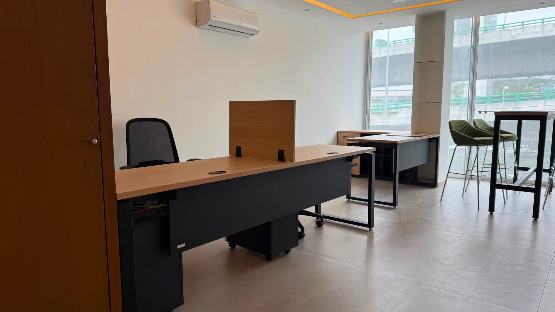 Oficina de Check Ing Entertainment con escritorios de madera, mesa alta y bancos verdes, por Poliarte