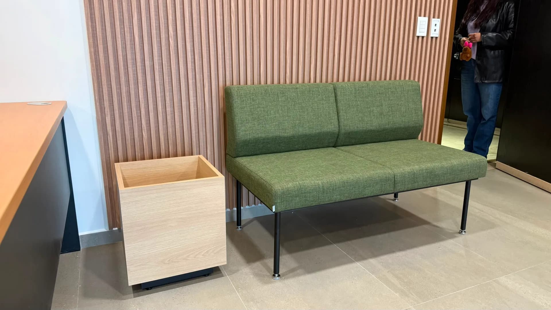 Sofá tapizado verde y cesto de madera en privado de Check Ing Entertainment, por Poliarte