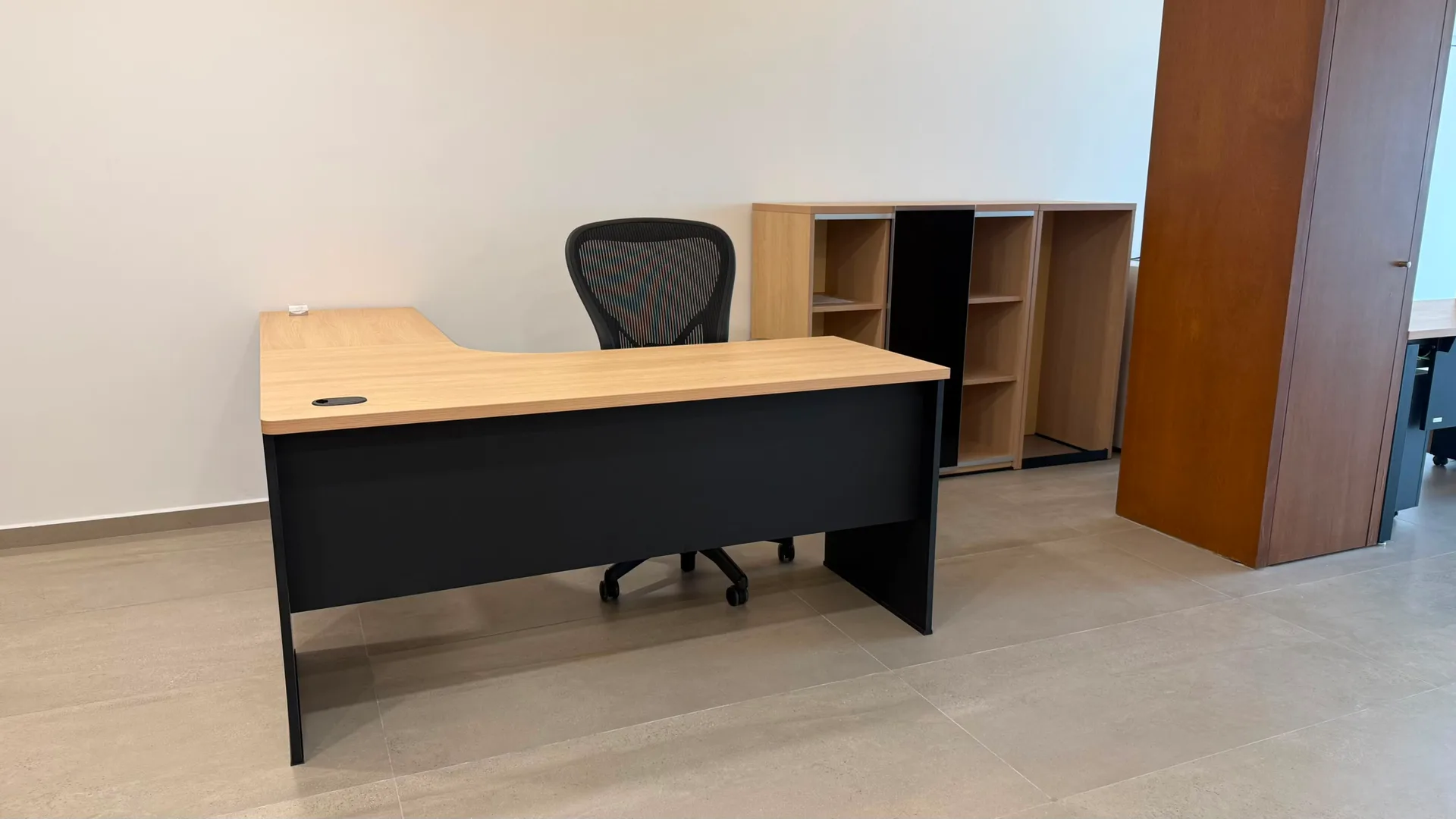 Escritorio en L de Check Ing Entertainment con cubierta de madera, librero y silla de malla, por Poliarte