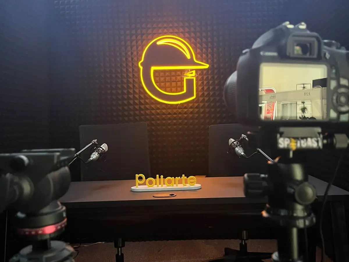 Set de grabación del podcast Gigantes de la Construcción en el stand, con el letrero de Poliarte sobre la mesa